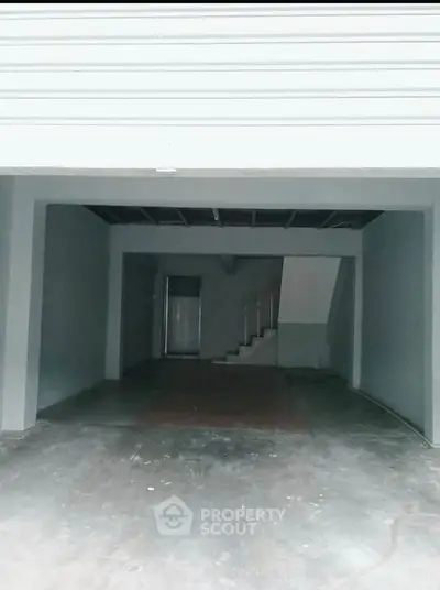 Spacious garage with concrete flooring and staircase access