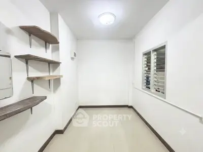 Minimalist room with white walls, shelves, and window, ideal for storage or small office space.