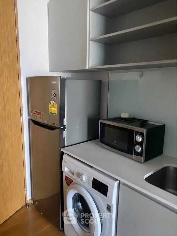 Compact kitchen with modern appliances including fridge, microwave, and washing machine.