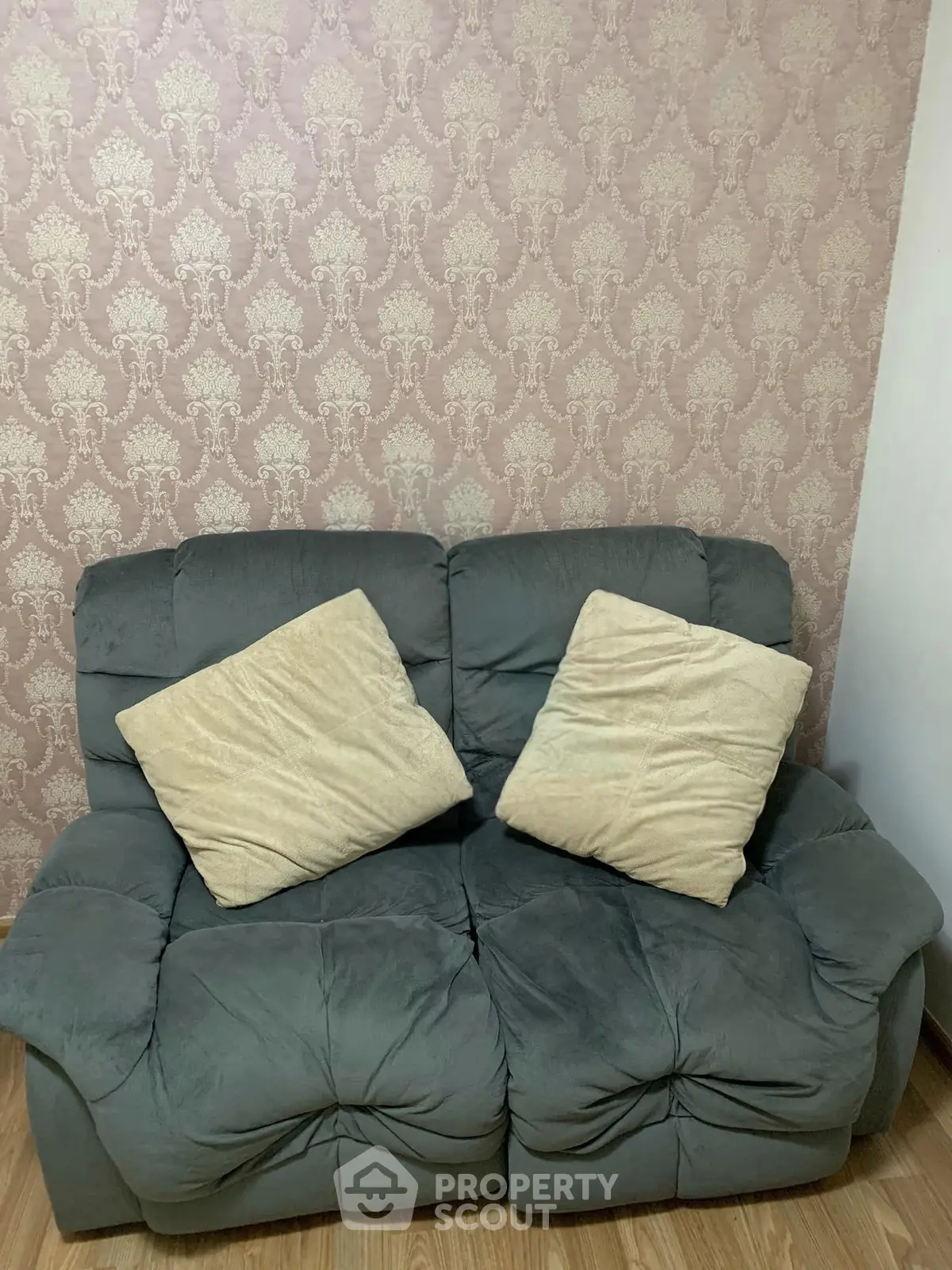 Cozy living room with plush gray sofa and elegant wallpaper, perfect for relaxation.