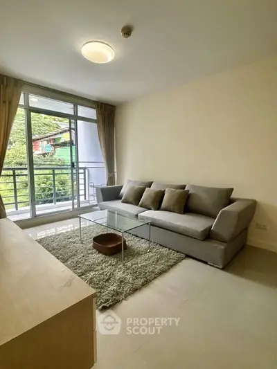 Spacious living room with modern sofa and large window offering lush green views.
