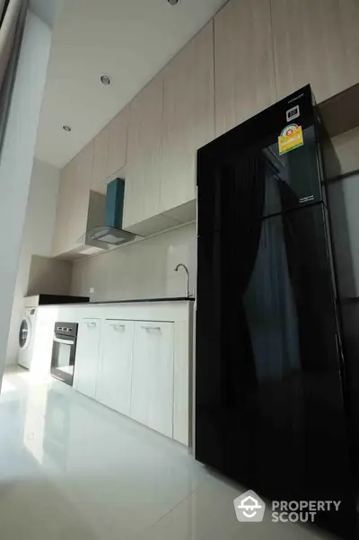 Modern kitchen with sleek black fridge and built-in oven in stylish apartment.