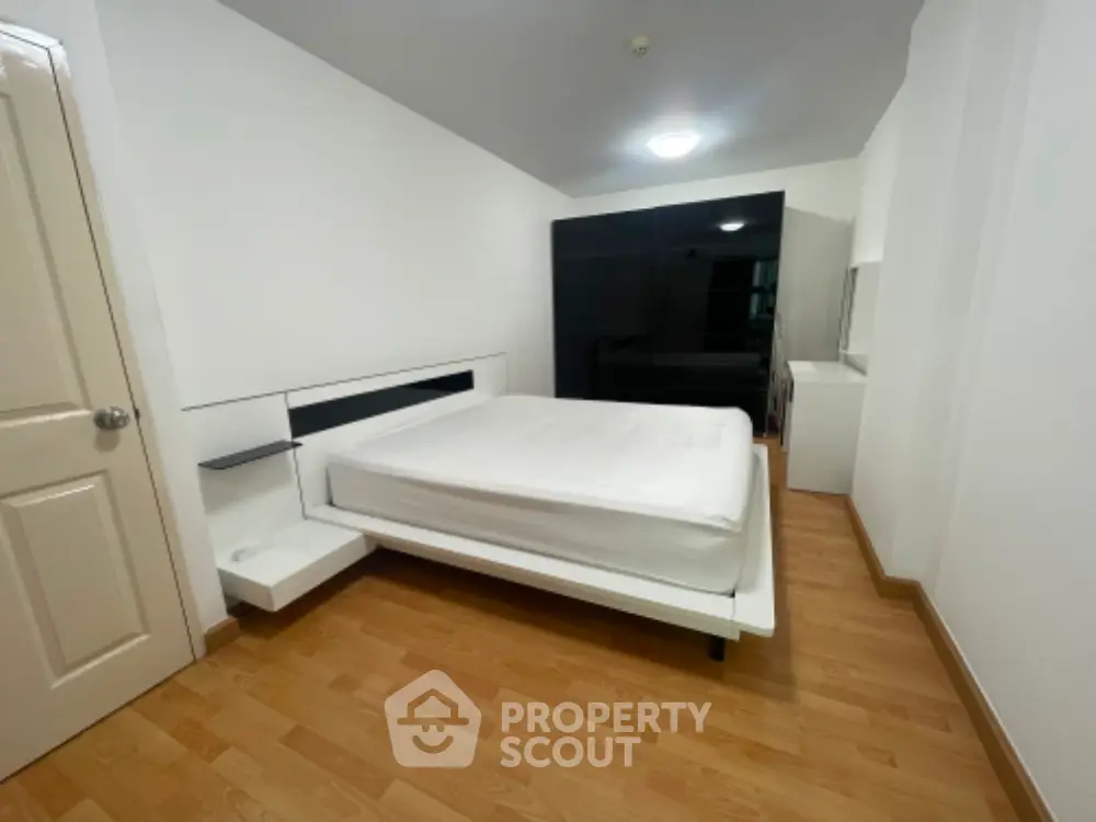 Modern minimalist bedroom with sleek black wardrobe and wooden flooring