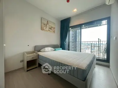 Modern bedroom with large window and city view, featuring a comfortable bed and stylish decor.