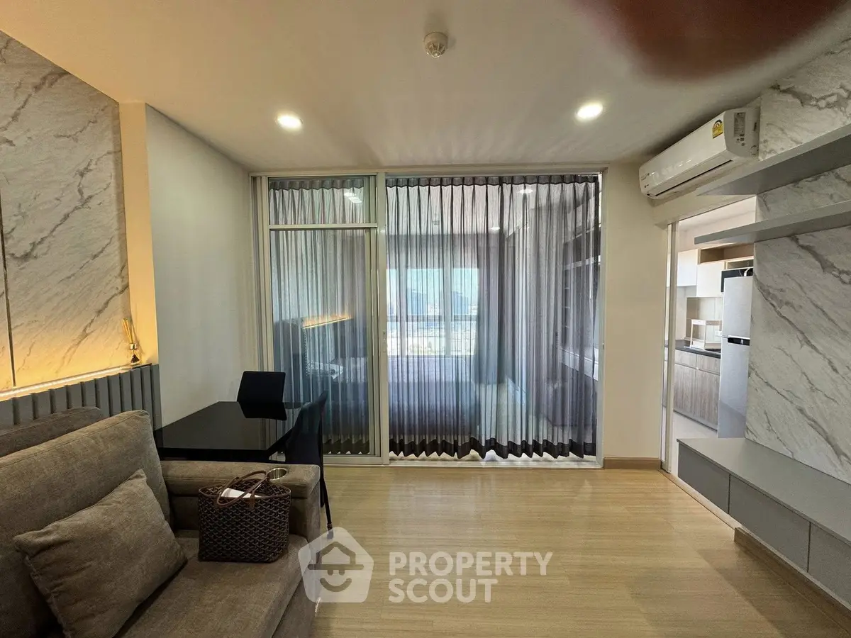 Modern living room with stylish decor and open kitchen layout, featuring sleek furniture and natural light.