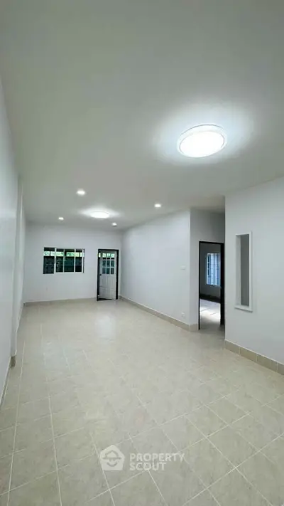 Spacious empty room with tiled flooring and modern lighting, ideal for customization.