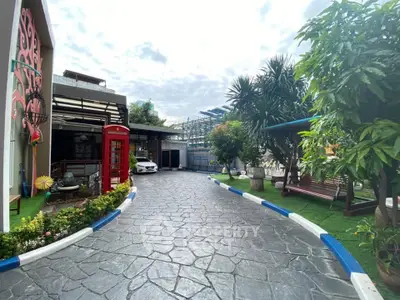 Charming garden entrance with lush greenery and unique phone booth feature.