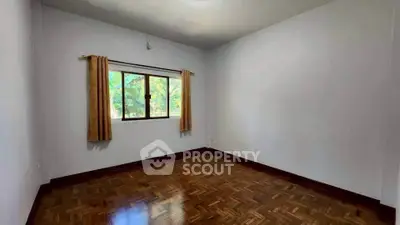 Spacious empty room with parquet flooring and window view
