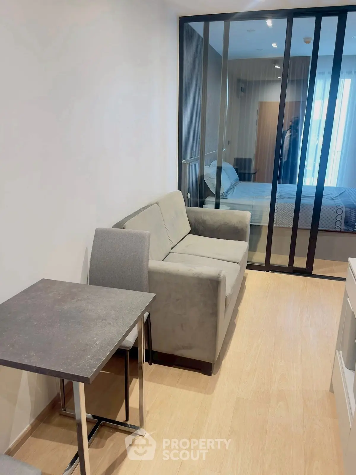 Modern studio apartment with cozy living area and sliding glass partition to bedroom.