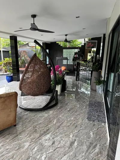 Luxurious modern living room with marble flooring, hanging chair, and lush greenery, perfect for relaxation and entertaining.