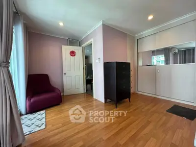 Spacious bedroom with wooden flooring and modern furniture in a cozy apartment.