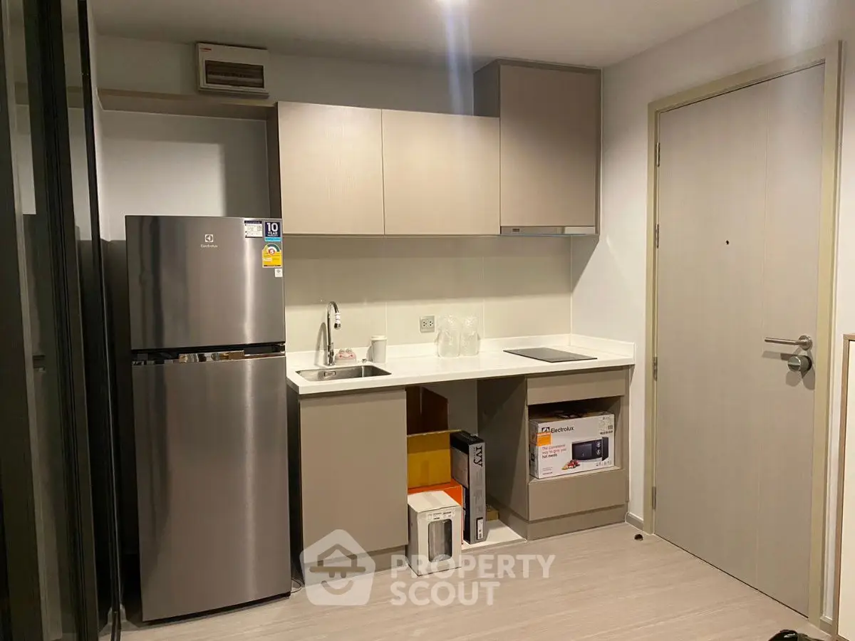 Modern compact kitchen with sleek cabinetry and stainless steel fridge