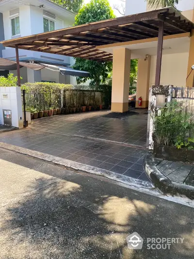 Spacious covered parking area with tiled flooring and lush greenery in a modern residential property.