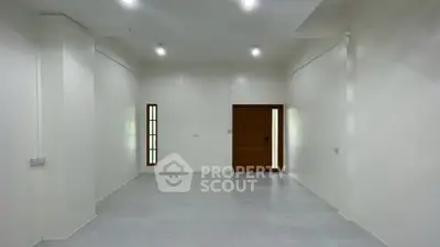 Spacious empty room with white walls and wooden door, ideal for customization.