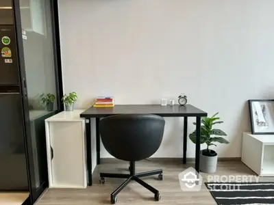 Modern study room with sleek black desk and chair, minimalist decor, and potted plants.