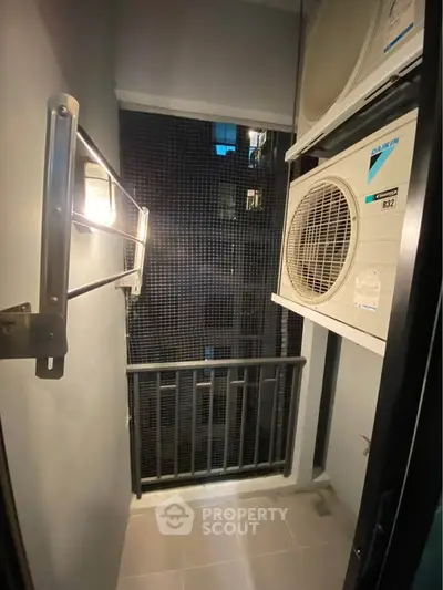 Compact balcony with air conditioning units and night view in modern apartment.