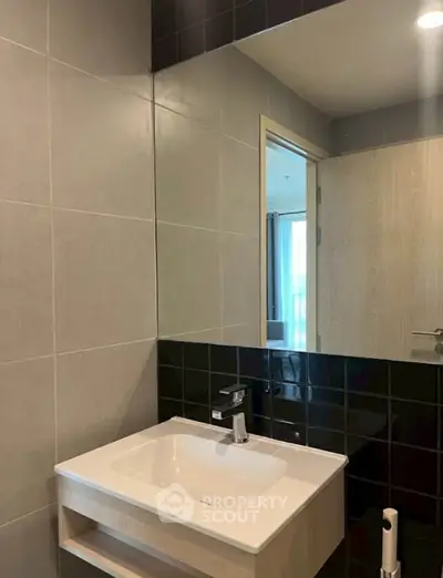 Modern bathroom with sleek sink and large mirror in stylish apartment.