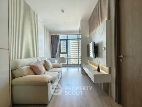 Modern living room with stylish decor and large windows offering city views.