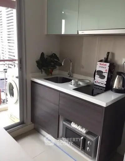 Modern compact kitchen with sleek cabinetry and balcony view, featuring built-in appliances and natural light.