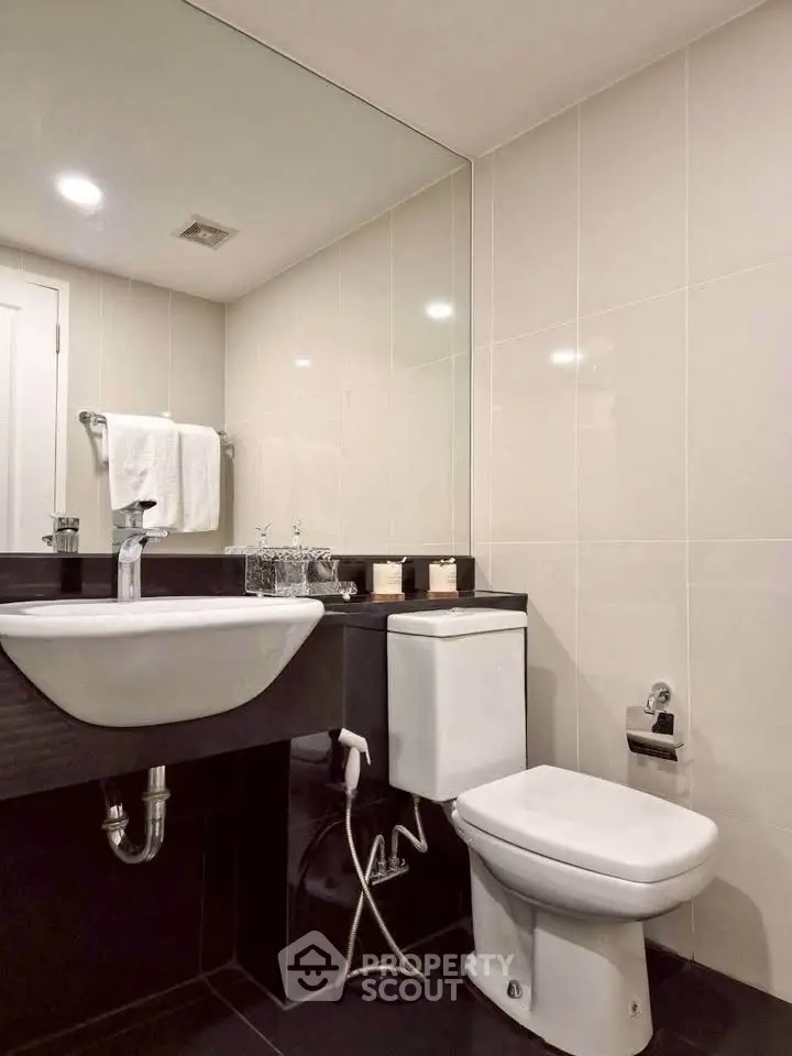 Modern bathroom with sleek fixtures and large mirror in a contemporary home.
