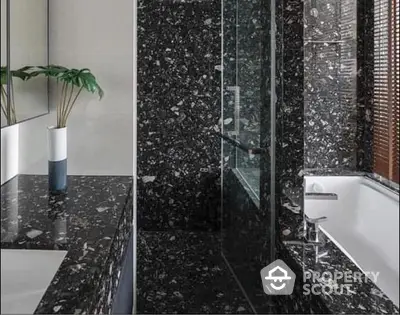 Luxurious bathroom with high-end black marble finishes, glass shower enclosure, and modern fixtures, perfect for upscale properties.