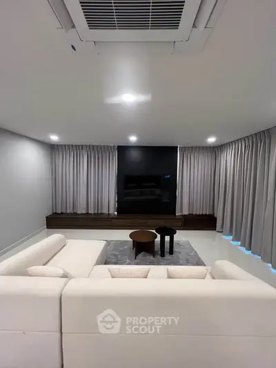 Modern living room with sleek design, featuring a white sofa, stylish coffee tables, and a wall-mounted TV.