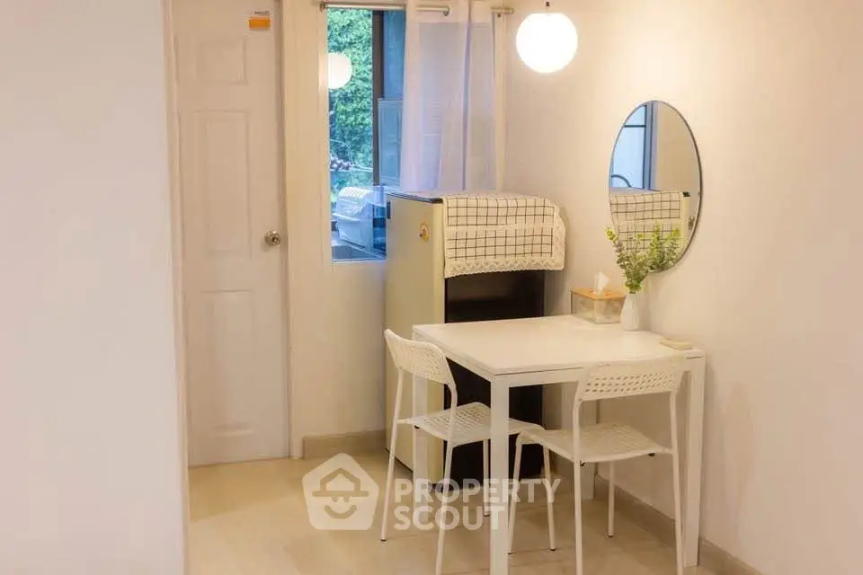 Cozy dining nook with modern white table and chairs, round mirror, and soft lighting.