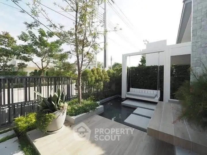 Modern outdoor garden with stylish seating and water feature in a contemporary home setting.