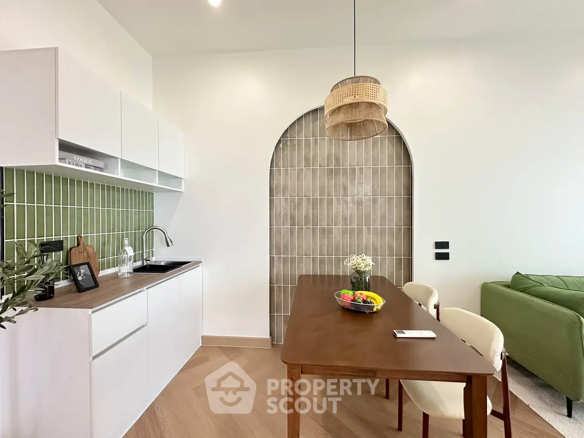 Modern kitchen with open layout and stylish dining area featuring green accents and wooden furniture.