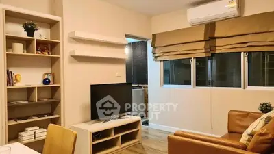 Modern living room with cozy seating and stylish decor, featuring a TV and air conditioning.