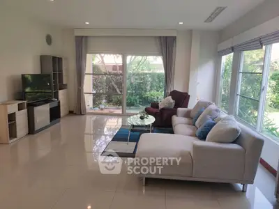 Spacious living room with modern furniture and large windows overlooking a lush garden.
