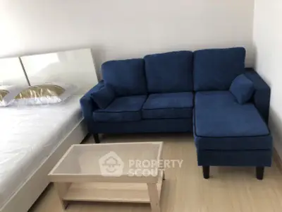 Modern bedroom with blue sofa and glass coffee table, perfect for cozy living.