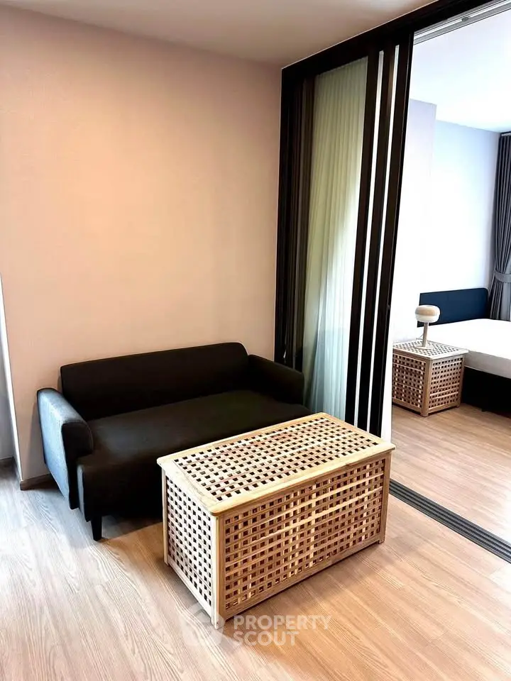 Modern apartment interior with cozy living room and stylish bedroom separated by sliding glass doors.