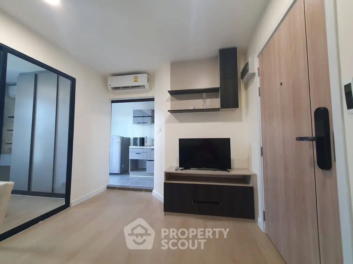Modern living room with sleek design and open kitchen view, featuring a TV unit and air conditioning.