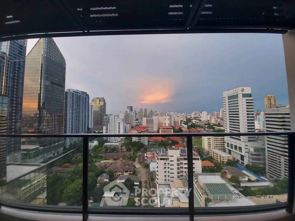 Stunning cityscape view from a high-rise balcony showcasing urban skyline at sunset.