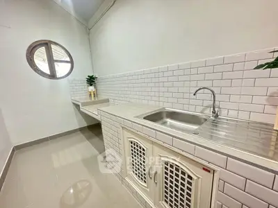 Modern kitchen with sleek white tiles and stainless steel sink