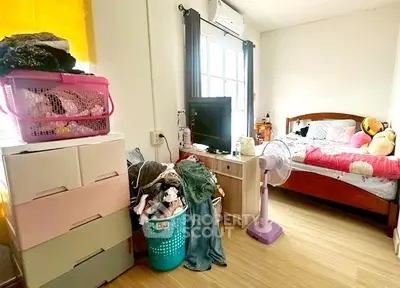Cozy bedroom with wooden flooring, bright window, and organized storage solutions.