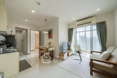 Modern open-plan living room with dining area and city view, featuring sleek furniture and natural light.