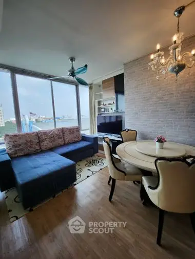 Elegant living room with modern furnishings, hardwood floors, and a charming chandelier, complemented by a large window offering ample natural light.