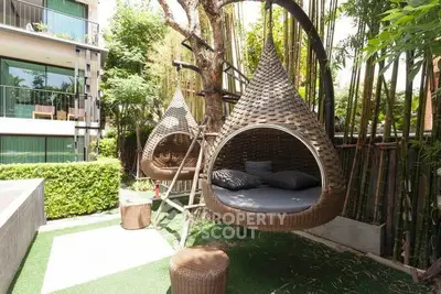 Luxurious garden with unique hanging wicker chairs and lush greenery in modern apartment complex.