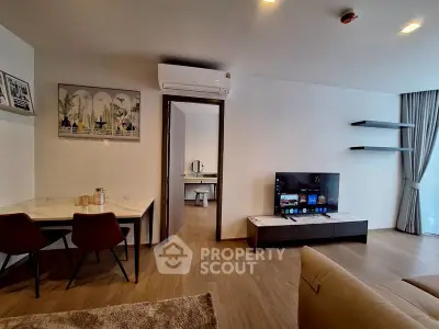 Modern living room with sleek furniture and TV, open layout to study area.