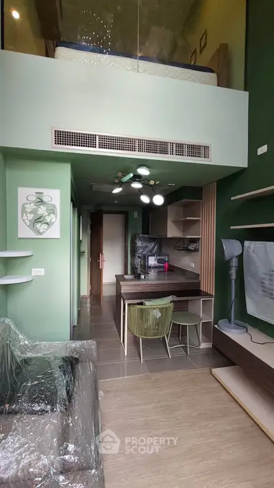 Modern loft apartment with stylish green interior and mezzanine bedroom, featuring open kitchen and cozy living area.