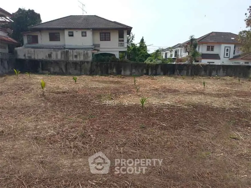 Vacant land plot in residential area with nearby houses, ideal for development.