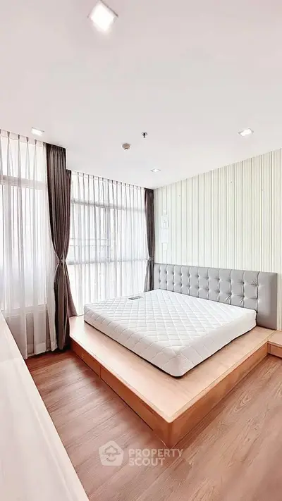 Spacious bedroom with modern design and large windows for natural light.