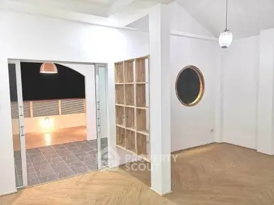 Modern minimalist living space with unique round window and open balcony access.