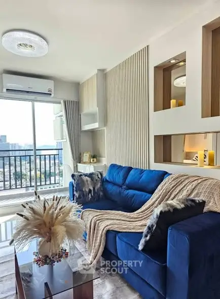 Modern living room with blue sofa and balcony view, featuring stylish decor and natural light.