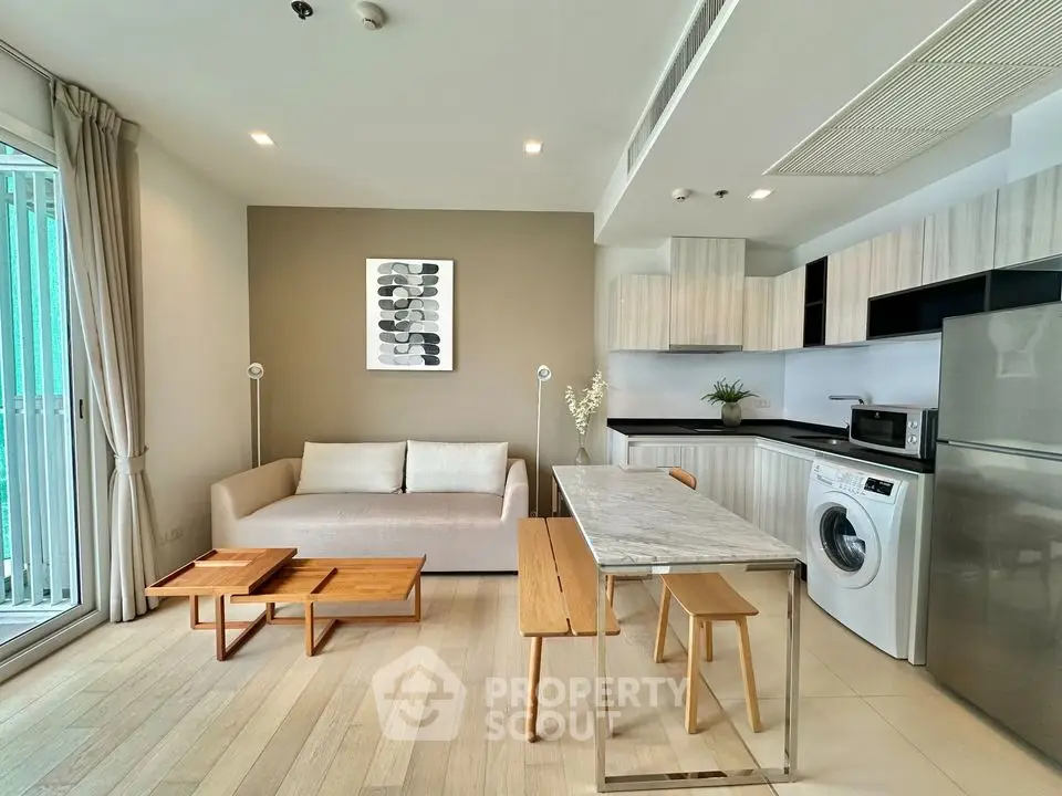 Modern open-plan living room with kitchen, featuring sleek furniture and appliances.