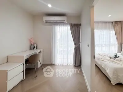 Modern bedroom with study area and natural light, featuring elegant decor and wooden flooring.