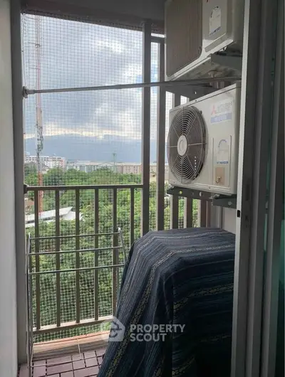 Compact balcony with air conditioning unit and scenic view of greenery and cityscape.