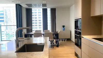 Luxurious modern kitchen with marble island and dining area in high-rise apartment with city view.